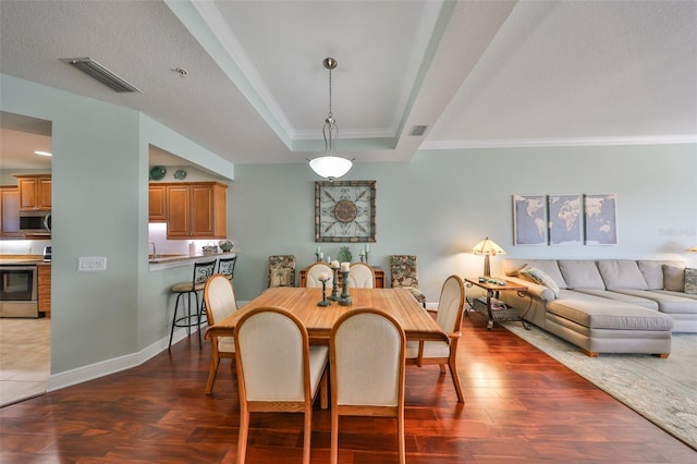 dining room featuring dark hardwood / wood-style flooring, crown molding, a raised ceiling, and a textured ceiling