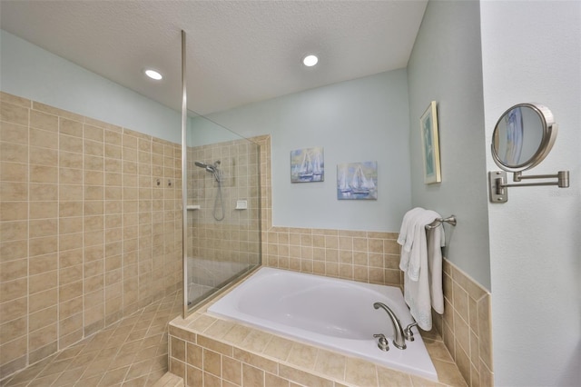 bathroom featuring a textured ceiling and separate shower and tub