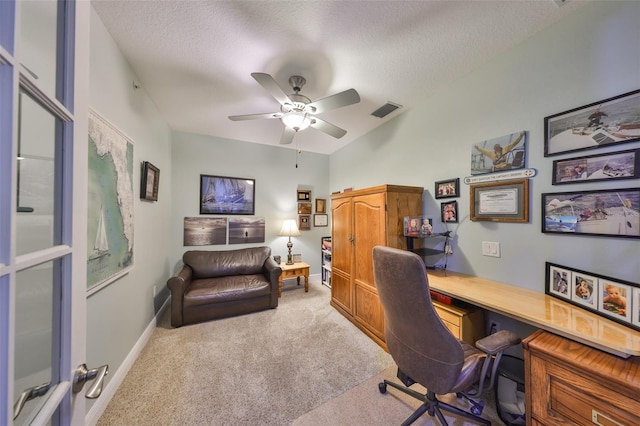 office space featuring ceiling fan, light colored carpet, and a textured ceiling