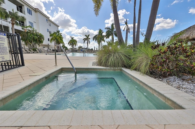 view of swimming pool featuring a hot tub and a water view