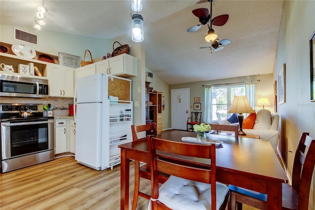 dining space with ceiling fan, lofted ceiling, and light hardwood / wood-style flooring