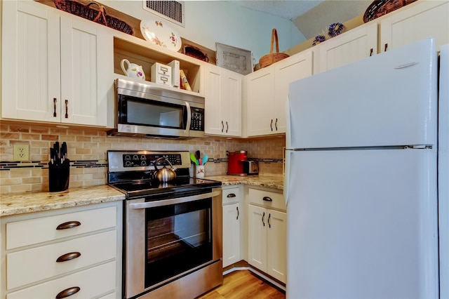 kitchen with light stone counters, white cabinetry, and appliances with stainless steel finishes