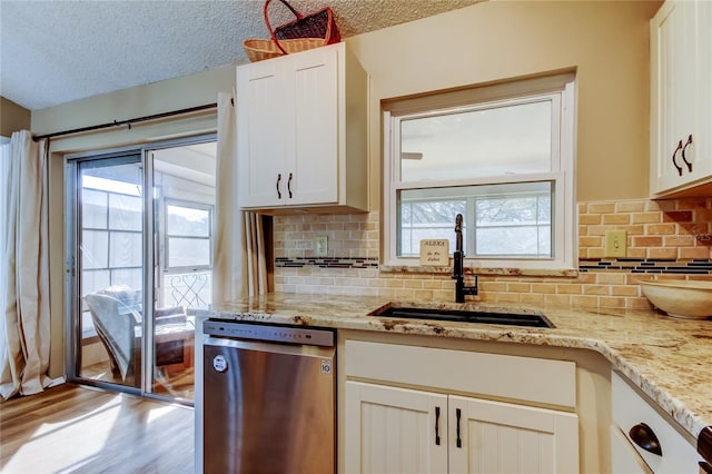 kitchen featuring sink, dishwasher, white cabinetry, light stone countertops, and a textured ceiling