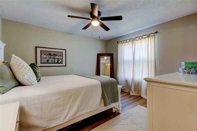 bedroom with ceiling fan, light wood-type flooring, and a textured ceiling