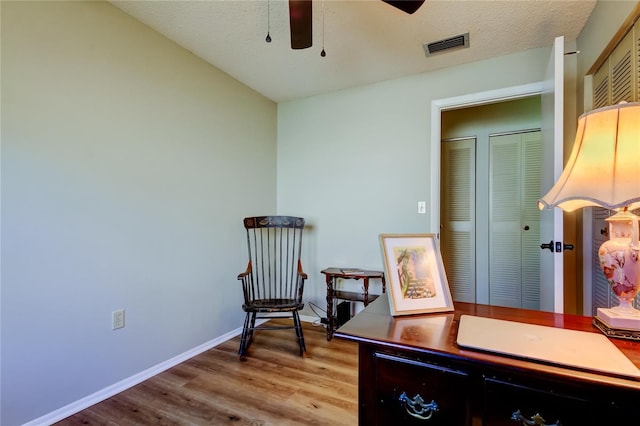 living area featuring a textured ceiling, light hardwood / wood-style floors, and ceiling fan