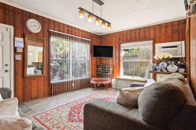 living room featuring a wall mounted air conditioner, a textured ceiling, and wood walls