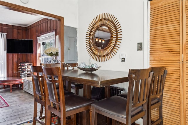 dining area with wood-type flooring, electric panel, and wood walls