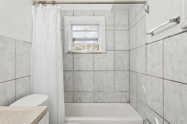 full bathroom featuring vanity, tile walls, toilet, and shower / bath combo