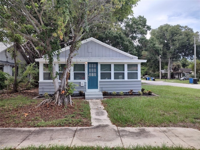 bungalow with board and batten siding, a front yard, and entry steps