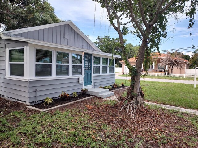 view of side of home with fence, board and batten siding, and a yard