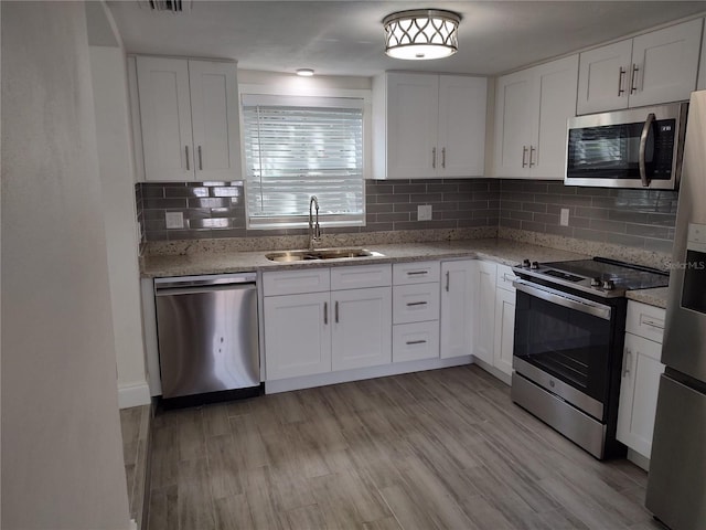 kitchen featuring stainless steel appliances, light wood-type flooring, white cabinets, and a sink