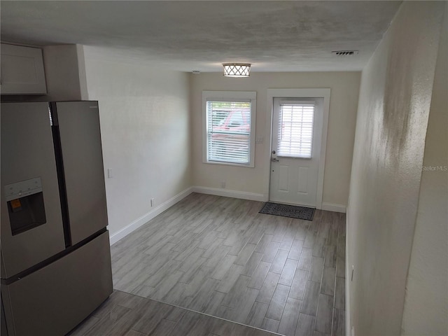 doorway with visible vents, baseboards, and wood finished floors