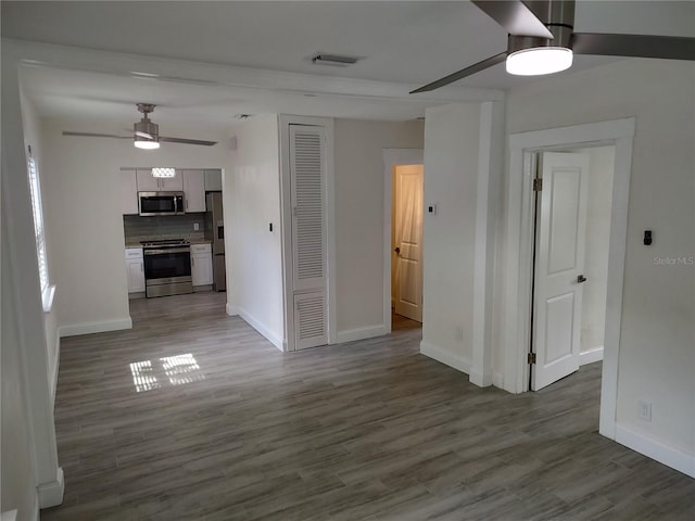 interior space featuring baseboards, wood finished floors, visible vents, and a ceiling fan