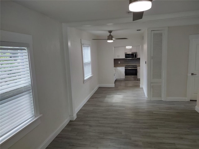 unfurnished living room featuring a ceiling fan, visible vents, baseboards, and dark wood-style flooring