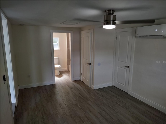 interior space featuring dark wood-style floors, baseboards, connected bathroom, and a wall mounted AC