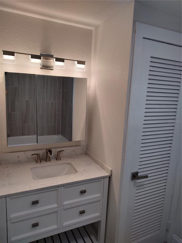 bathroom featuring a textured wall and vanity