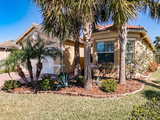 view of front of property featuring a garage, driveway, a front yard, and stucco siding