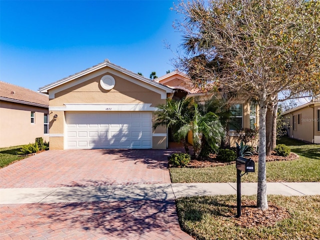 ranch-style home featuring a garage, decorative driveway, and stucco siding