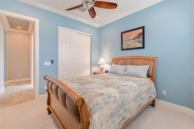 carpeted bedroom featuring baseboards, ornamental molding, ceiling fan, and a closet