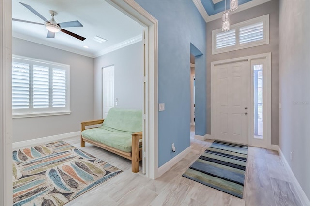 foyer entrance featuring ceiling fan, baseboards, and crown molding