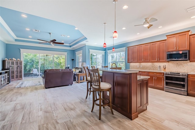 kitchen with visible vents, appliances with stainless steel finishes, backsplash, brown cabinetry, and a raised ceiling