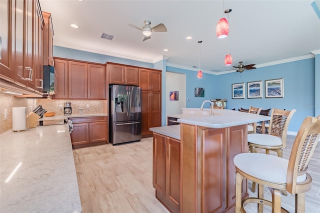 kitchen with a ceiling fan, brown cabinetry, visible vents, and stainless steel refrigerator with ice dispenser