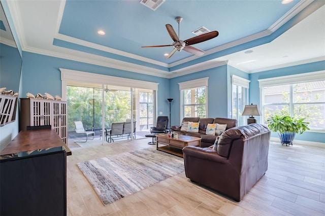 living room featuring ceiling fan, visible vents, a tray ceiling, and ornamental molding