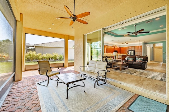 sunroom / solarium with a tray ceiling, visible vents, and ceiling fan