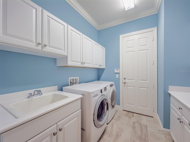 washroom with cabinet space, baseboards, independent washer and dryer, crown molding, and a sink