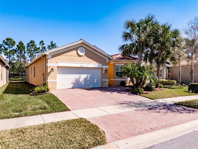 ranch-style home featuring an attached garage, a front lawn, decorative driveway, and stucco siding