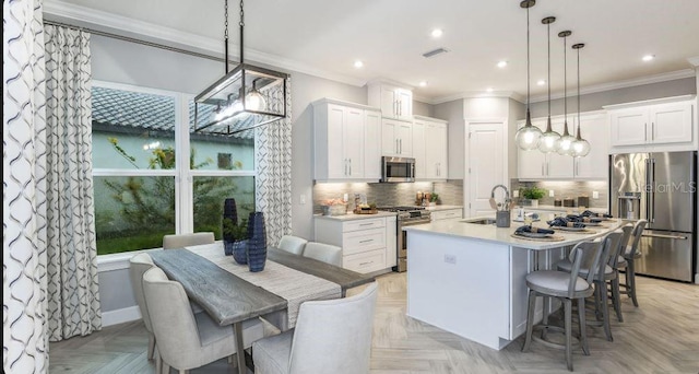 kitchen featuring hanging light fixtures, white cabinets, light parquet floors, and appliances with stainless steel finishes