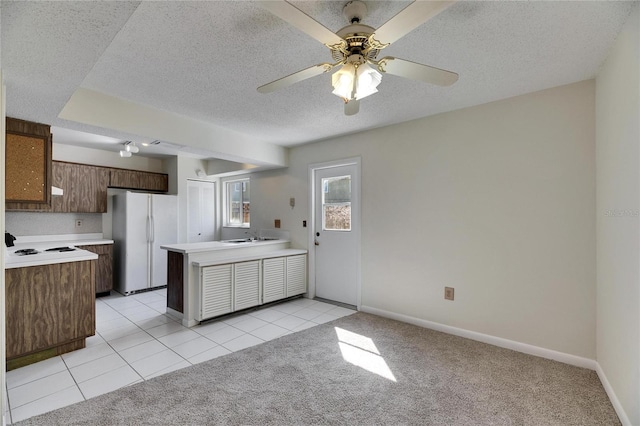 kitchen with ceiling fan, white refrigerator, a textured ceiling, light colored carpet, and kitchen peninsula