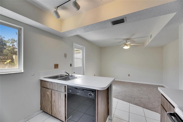 kitchen with sink, light carpet, kitchen peninsula, black dishwasher, and ceiling fan