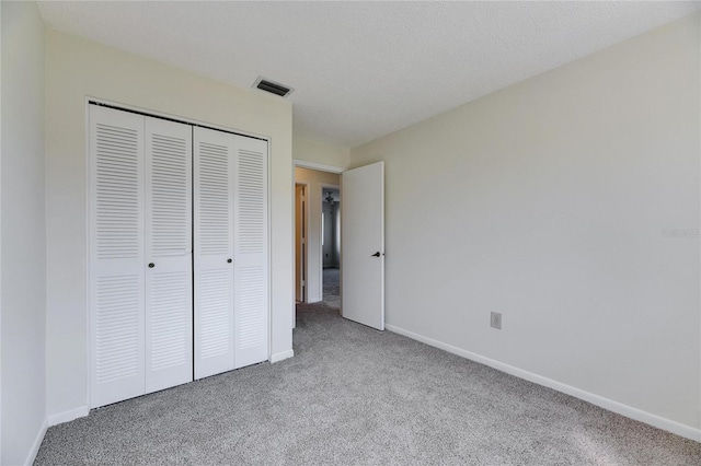 unfurnished bedroom featuring light colored carpet, a closet, and a textured ceiling