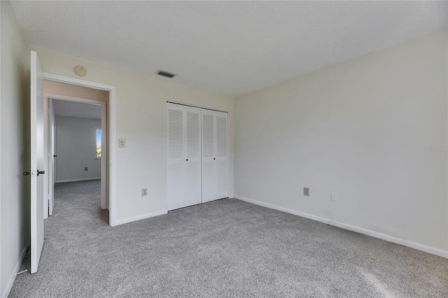 unfurnished bedroom featuring carpet, a textured ceiling, and a closet