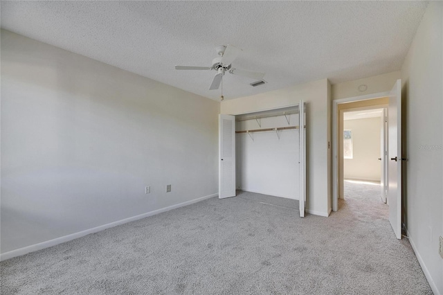 unfurnished bedroom with ceiling fan, a closet, light carpet, and a textured ceiling