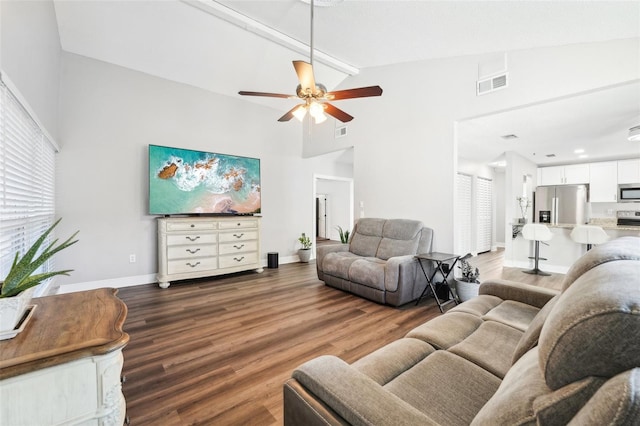 living room with ceiling fan, high vaulted ceiling, dark wood-type flooring, and beam ceiling