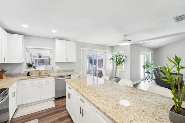 kitchen with white cabinets, stainless steel appliances, light stone countertops, and sink