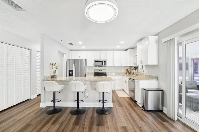 kitchen with white cabinets, appliances with stainless steel finishes, and light stone counters