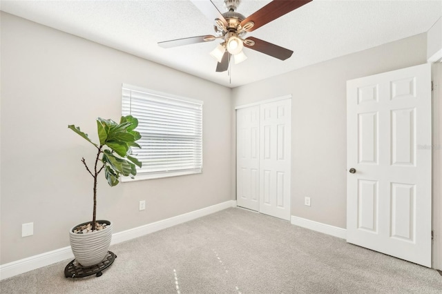 unfurnished bedroom featuring ceiling fan, a textured ceiling, light carpet, and a closet