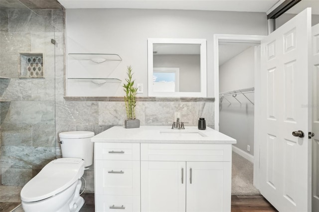 bathroom featuring toilet, tile walls, walk in shower, and vanity