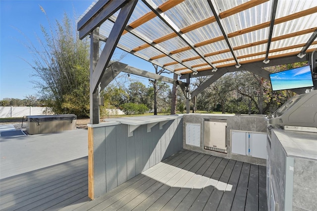 wooden deck with a pergola, exterior kitchen, and a hot tub