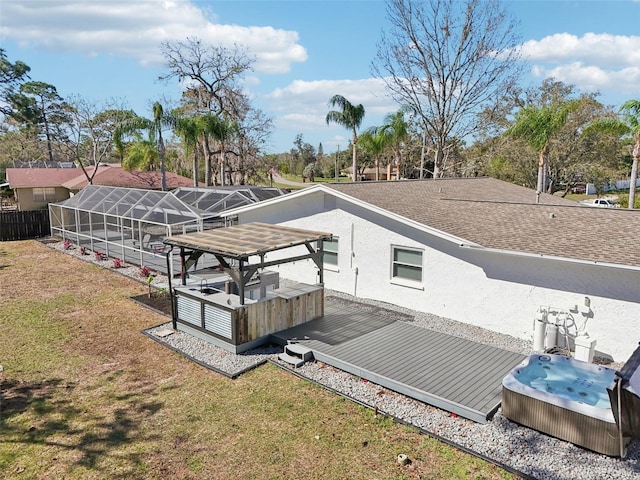 exterior space featuring a hot tub, a deck, a lanai, and a lawn