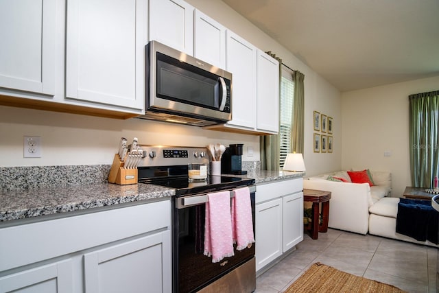 kitchen with light stone countertops, light tile patterned floors, stainless steel appliances, and white cabinets