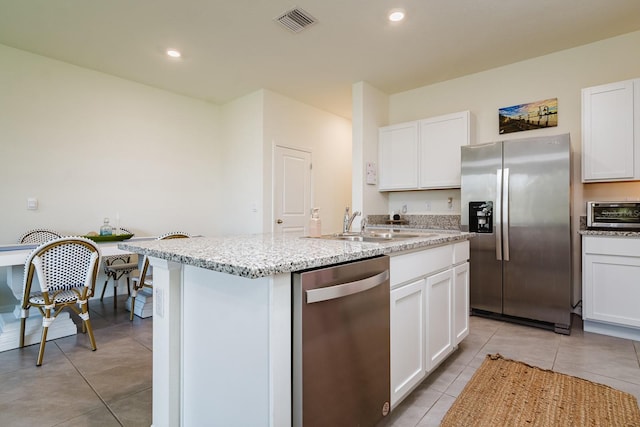 kitchen featuring appliances with stainless steel finishes, a center island with sink, and white cabinets