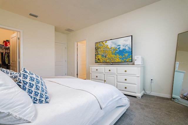 carpeted bedroom featuring a walk in closet and a closet