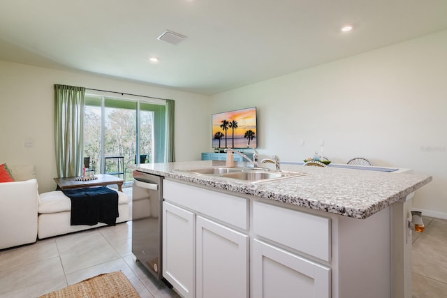 kitchen with sink, light tile patterned floors, dishwasher, a kitchen island with sink, and white cabinets