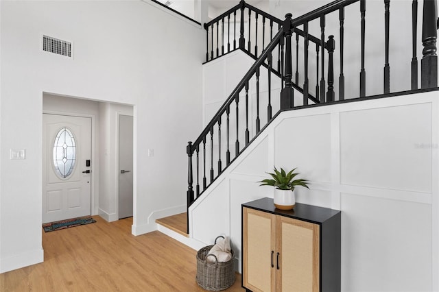 entryway with a towering ceiling and light hardwood / wood-style flooring