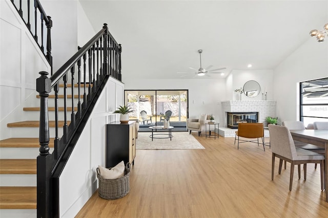 staircase featuring hardwood / wood-style flooring, ceiling fan, and a fireplace