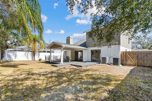 rear view of property featuring central AC unit, a yard, and a wooden deck